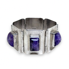 Silver bracelet with purple stones on a white background