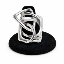 Silver ring with black center on a black stand against a white background