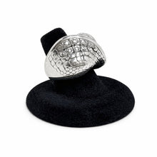 Silver ring with textured design on a black stand against a white background